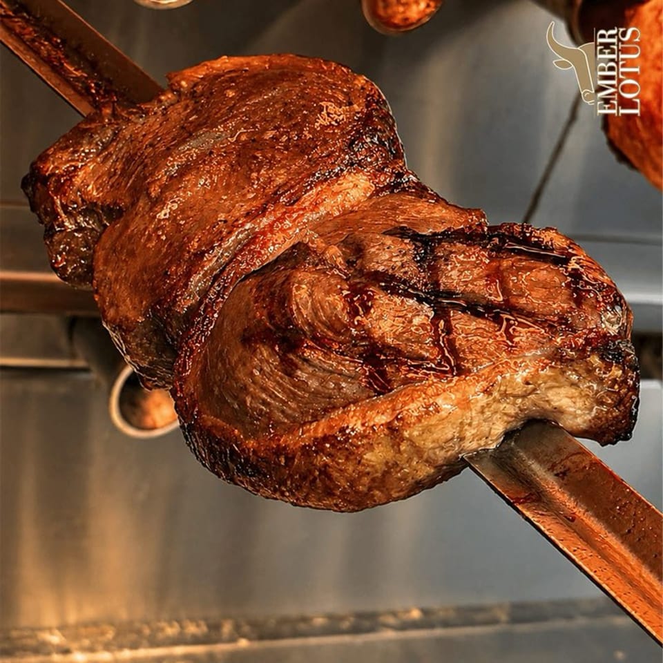 Close-up of roasted meat on a rodizio skewer at Ember Lotus.